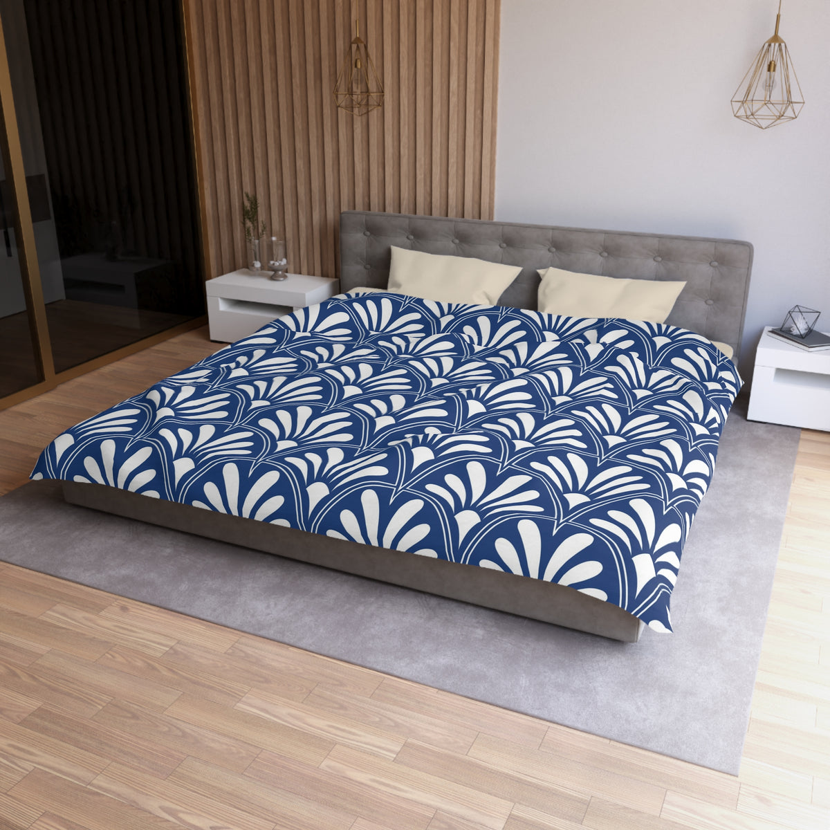 a modern bedroom with a large bed featuring a blue and white patterned comforter. The bed is positioned against a wall with a wooden panel, and there are two nightstands on either side of the bed. The room has a minimalist and clean design, with a gray headboard and a wooden floor.