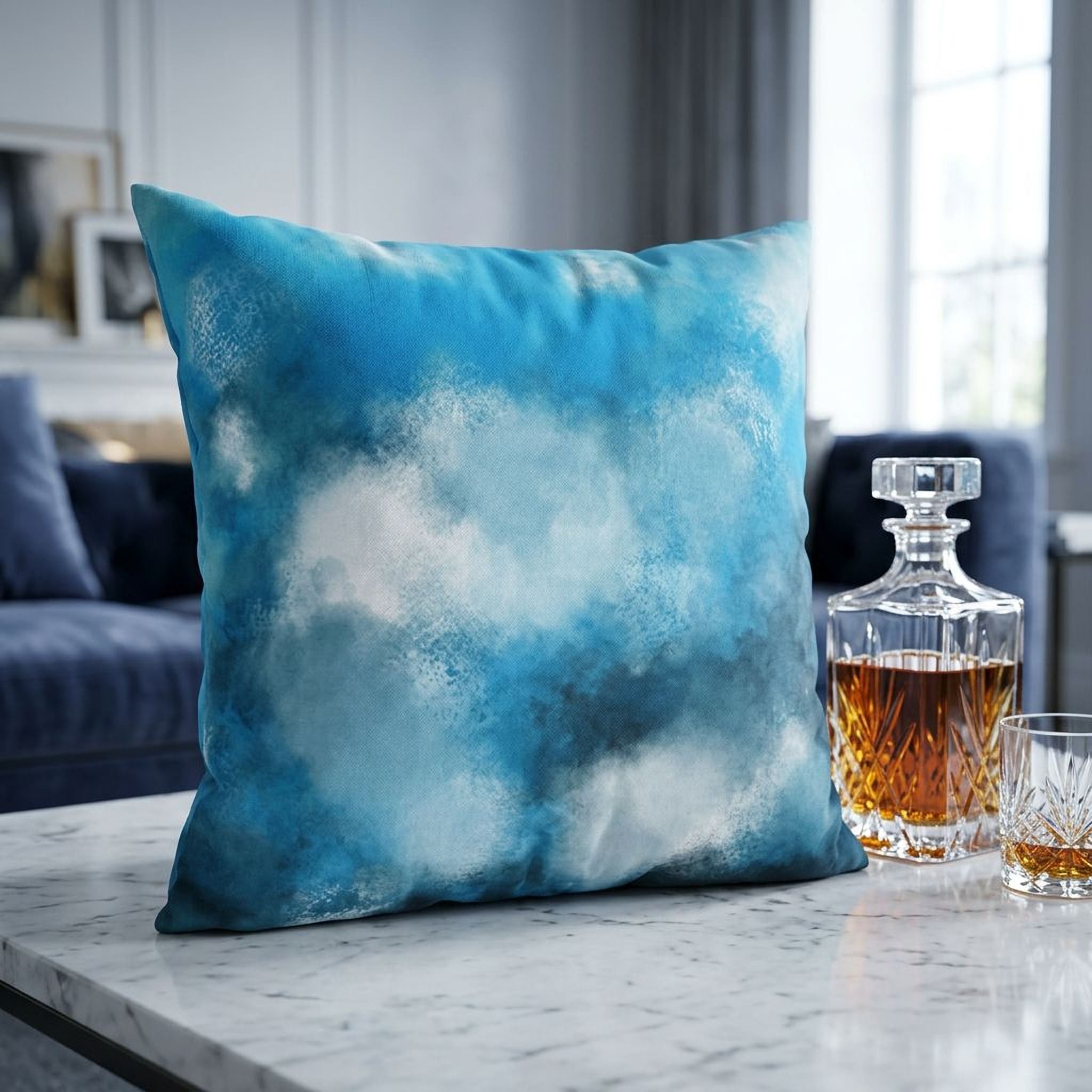a blue and white throw pillow on a white marble table, with a glass of whiskey and a bottle of whiskey next to it.