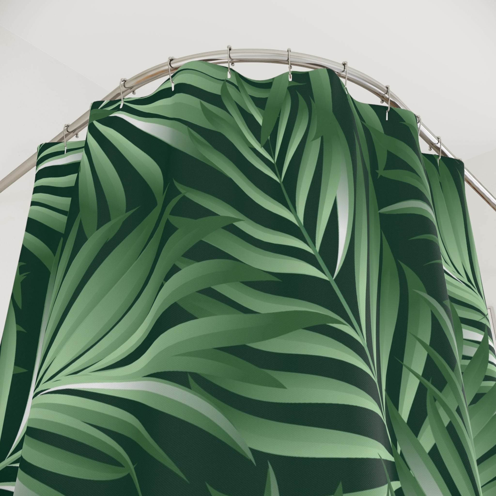 a shower curtain with a tropical leaf pattern in shades of green.
