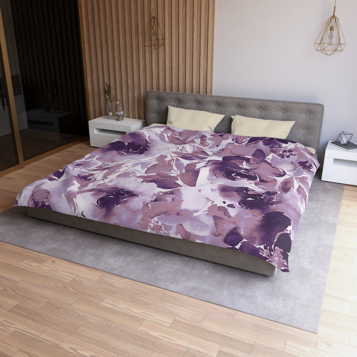 a modern bedroom with a large bed covered in a purple and white floral comforter. The bed is positioned against a wall with a wooden panel. The room also features a nightstand, a pendant light, and a mirror.
