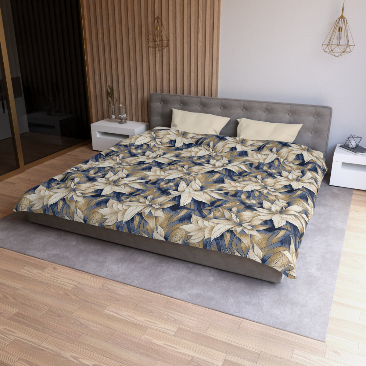 a modern bedroom with a large bed covered in a floral print comforter. The bed is positioned against a wall with a wooden panel. The room has a minimalist design, with a gray headboard and white nightstands. There is a pendant light hanging above the bed, and a vase on one of the nightstands. The overall color scheme of the room is neutral, with the floral print adding a touch of nature and warmth to the space.