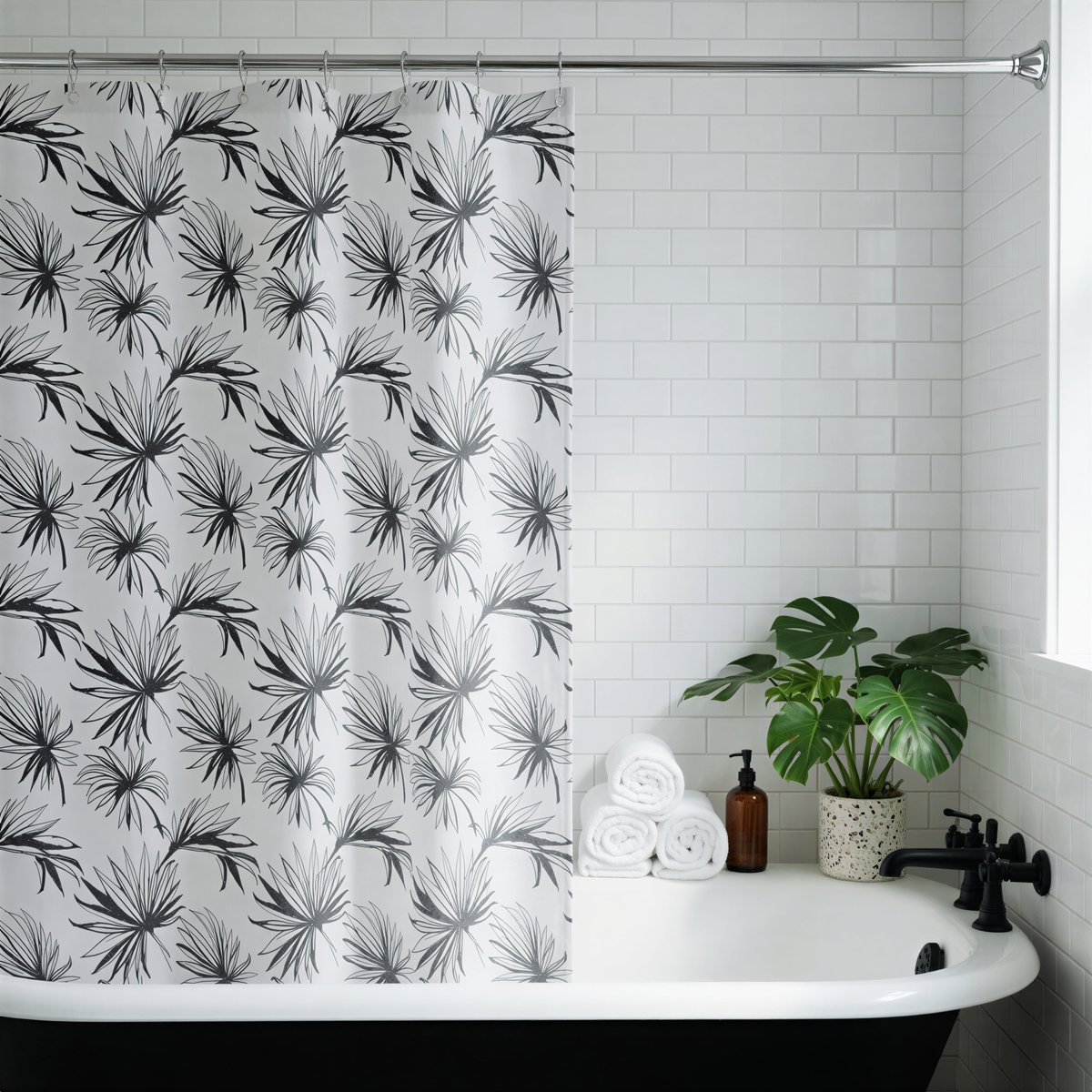 a bathroom with a white bathtub, a black and white patterned shower curtain, a potted plant, and rolled towels on the counter.
