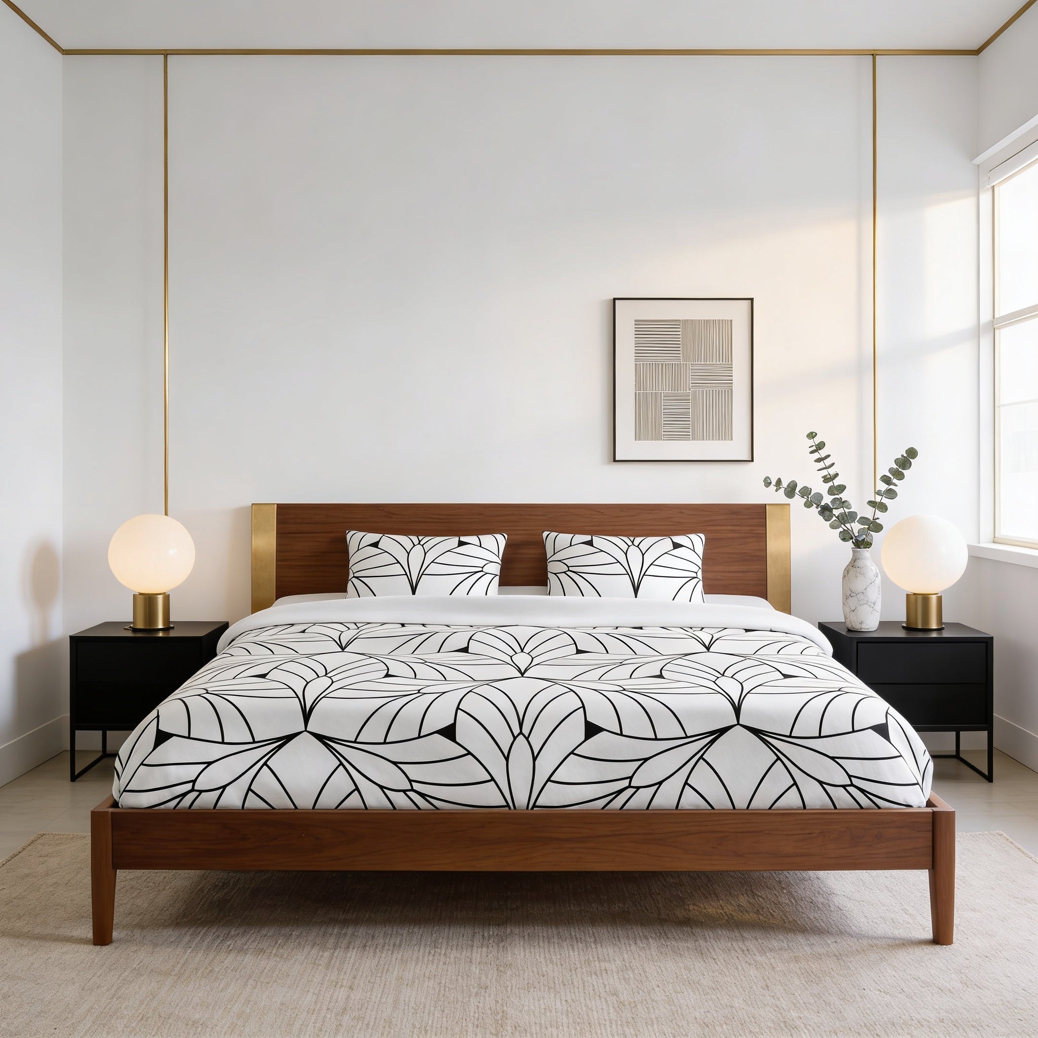 a modern bedroom with a large bed, wooden headboard, and a black nightstand on each side. The bed has a white and black leaf-patterned comforter and matching pillows. The room has white walls and a large window, allowing natural light to fill the space. There are two round lamps on the nightstands, and a framed artwork hangs on the wall above the bed.