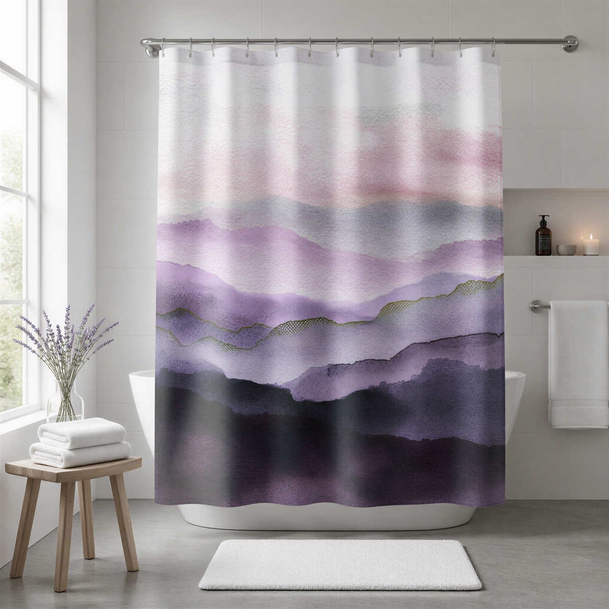 a bathroom with a shower curtain that has a purple and pink watercolor mountain landscape design. The curtain is hanging from a rod above a white bathtub. There is a small table with a vase of flowers next to the bathtub, and a white rug on the floor in front of the bathtub.