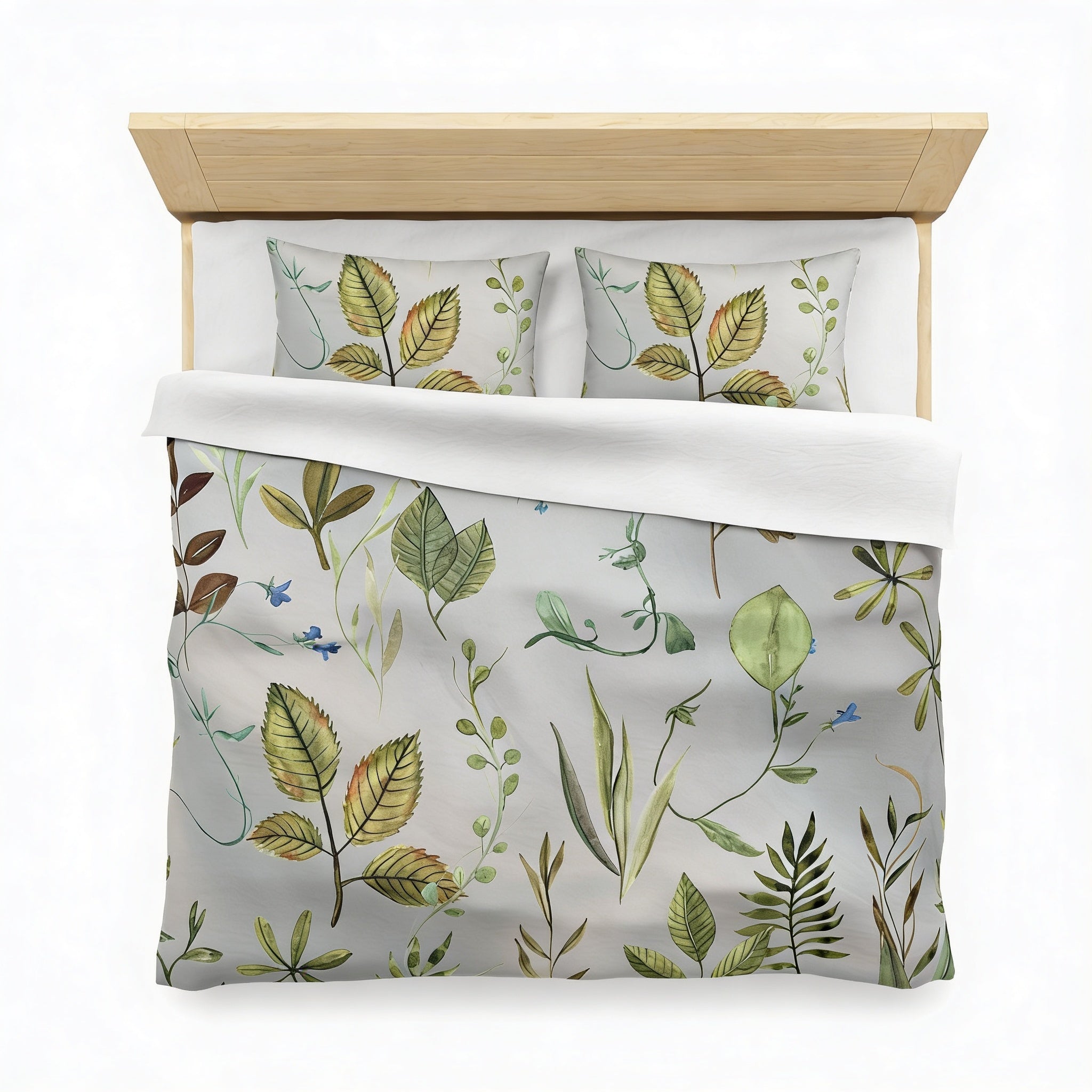 a bed with a gray comforter and pillows featuring a pattern of green leaves and plants.