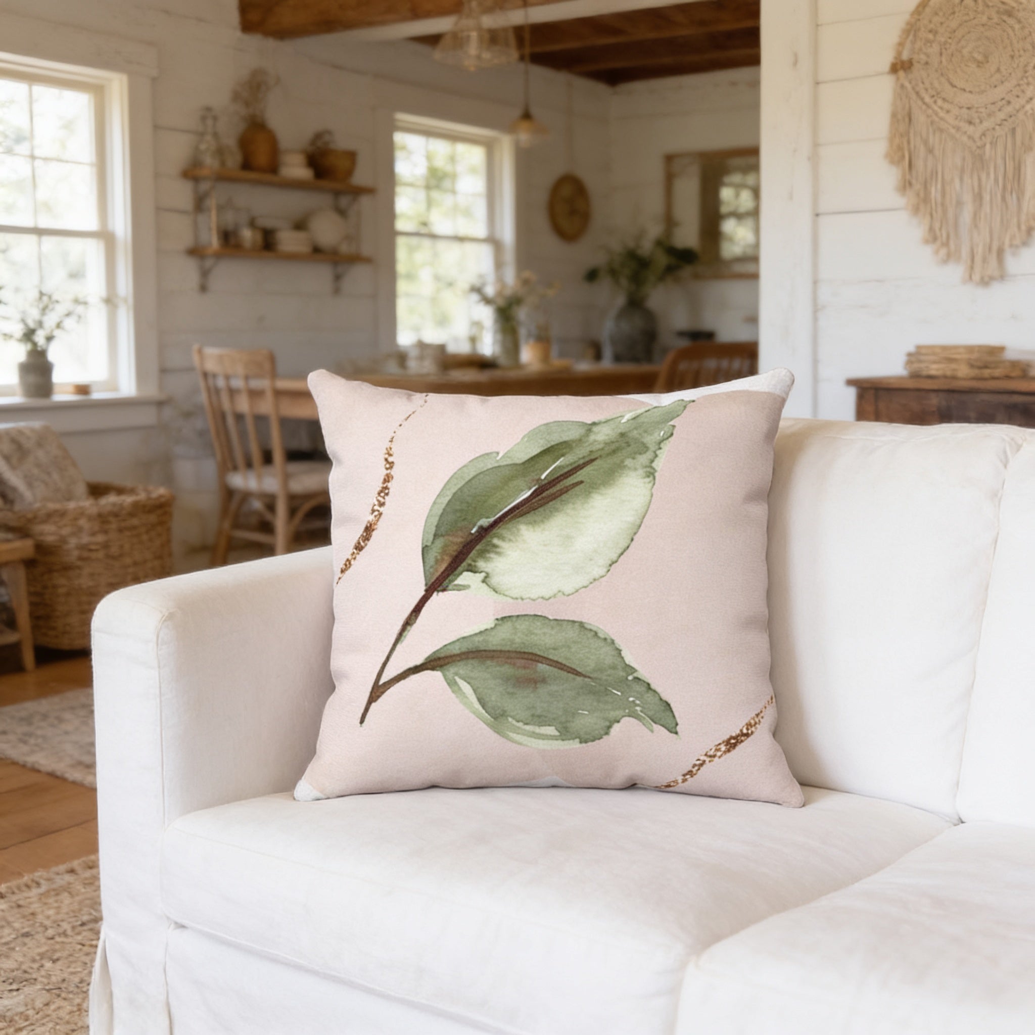 a living room with a white sofa and a decorative pillow with a leaf design on it.