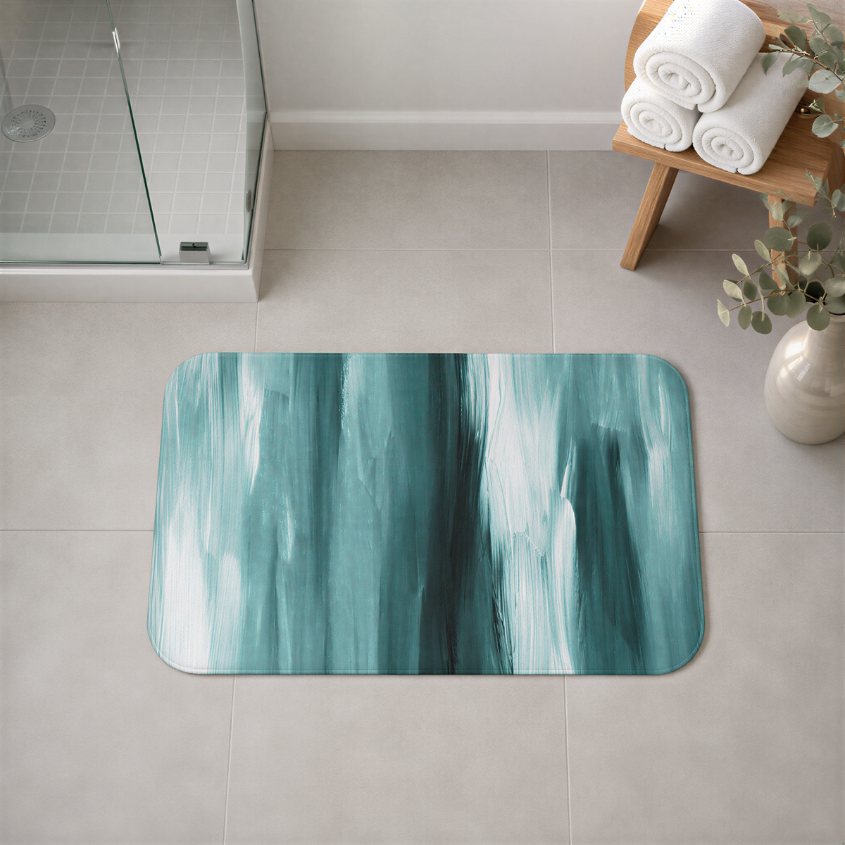 a bathroom with a green and white abstract design rug on the floor, a glass shower door, a wooden bench with rolled towels, and a vase with greenery.