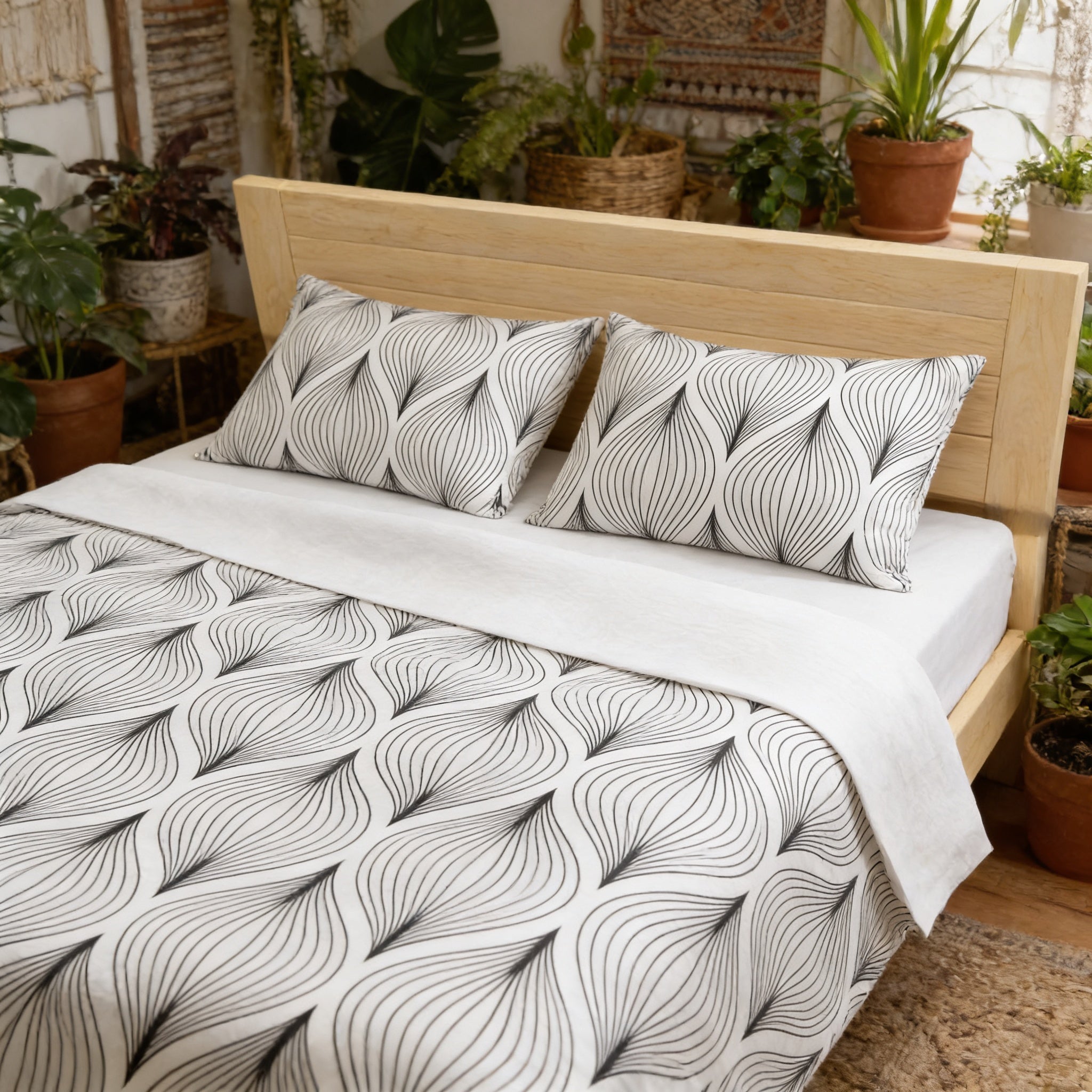a bedroom with a wooden bed frame, a black and white patterned comforter, and two matching pillows. The room is decorated with various potted plants, creating a cozy and natural atmosphere.