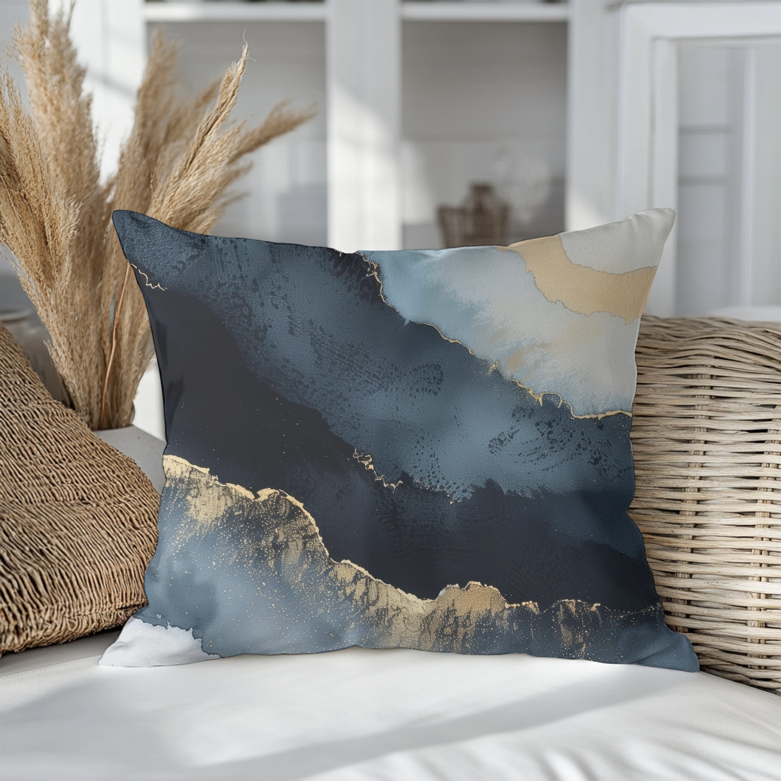 a decorative pillow with a striking abstract design in shades of blue and gold, placed on a white surface.