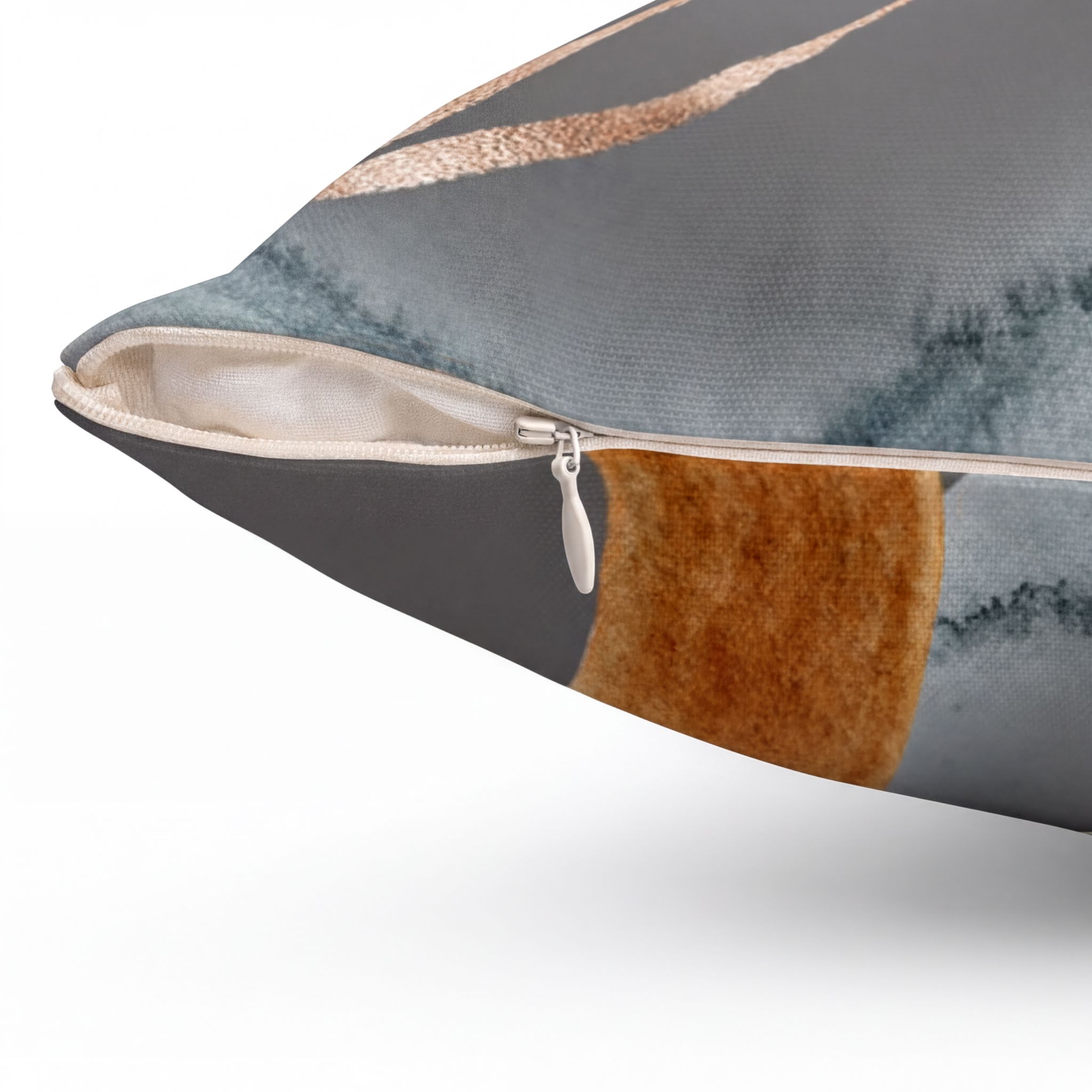 a close-up view of a pillow with a metallic zipper pull and a patterned fabric.