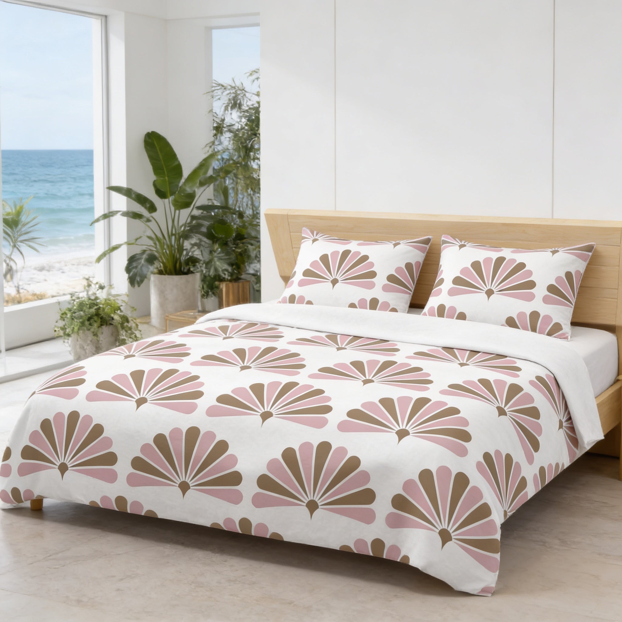 a bedroom with a large bed featuring a white comforter with a pink and brown floral pattern. The bed is positioned against a wall with a window overlooking the ocean. The room also includes potted plants and a wooden headboard.