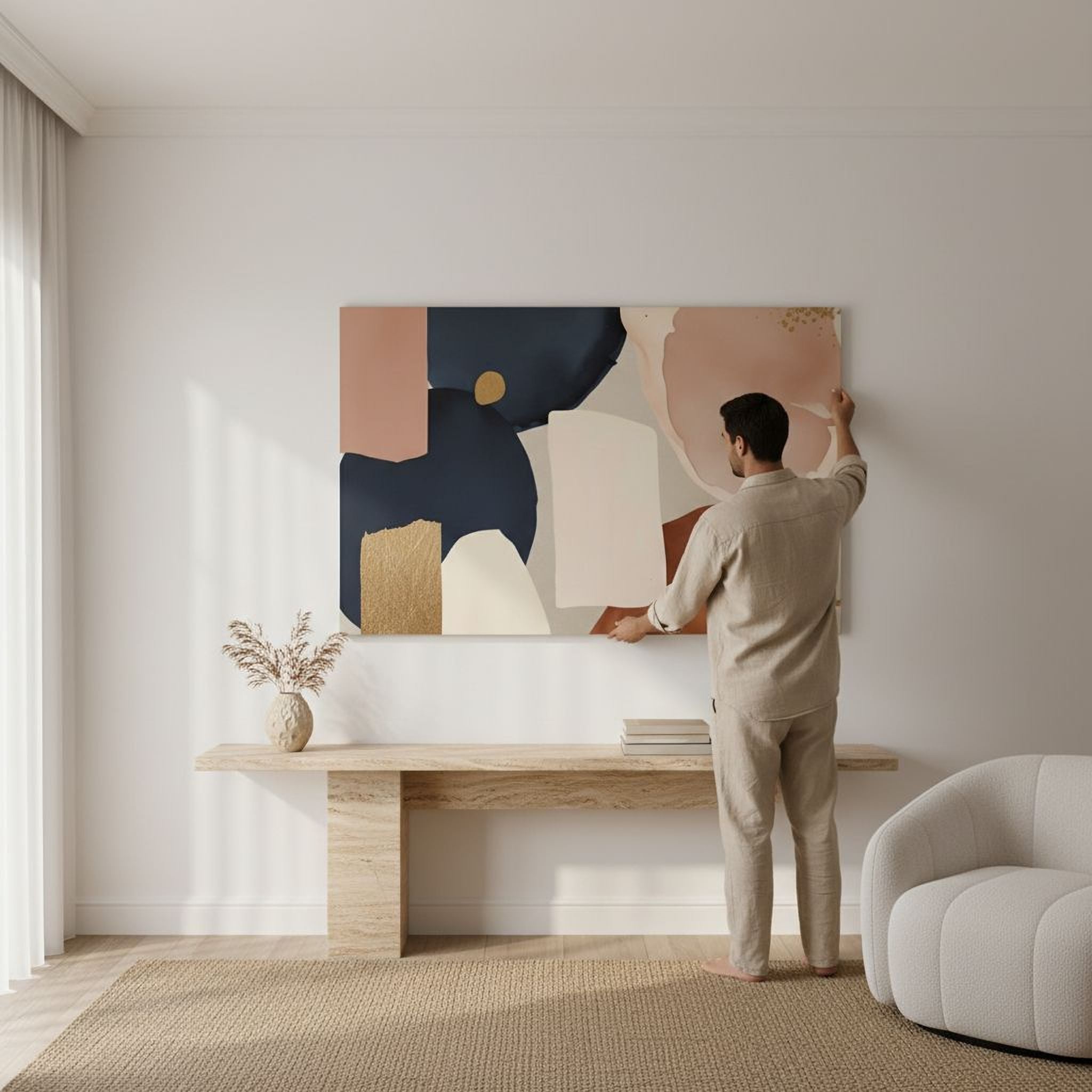 A man is standing in a living room, hanging a large abstract painting on the wall.