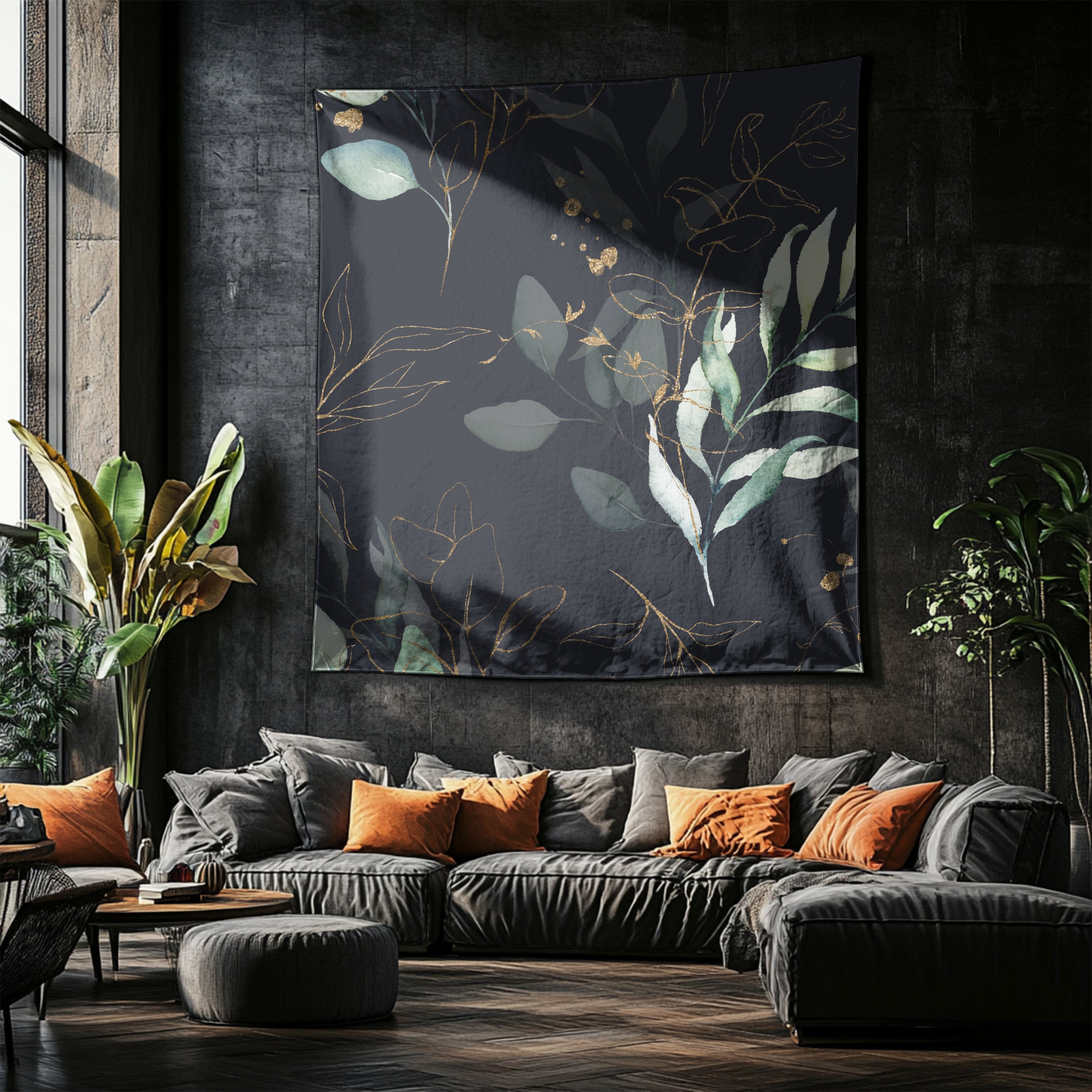 a modern living room with a large black and gold tapestry hanging on the wall, featuring a leafy pattern. The room is furnished with a gray sofa, orange throw pillows, and a wooden coffee table. The space is illuminated by natural light coming through a window, creating a cozy and inviting atmosphere.