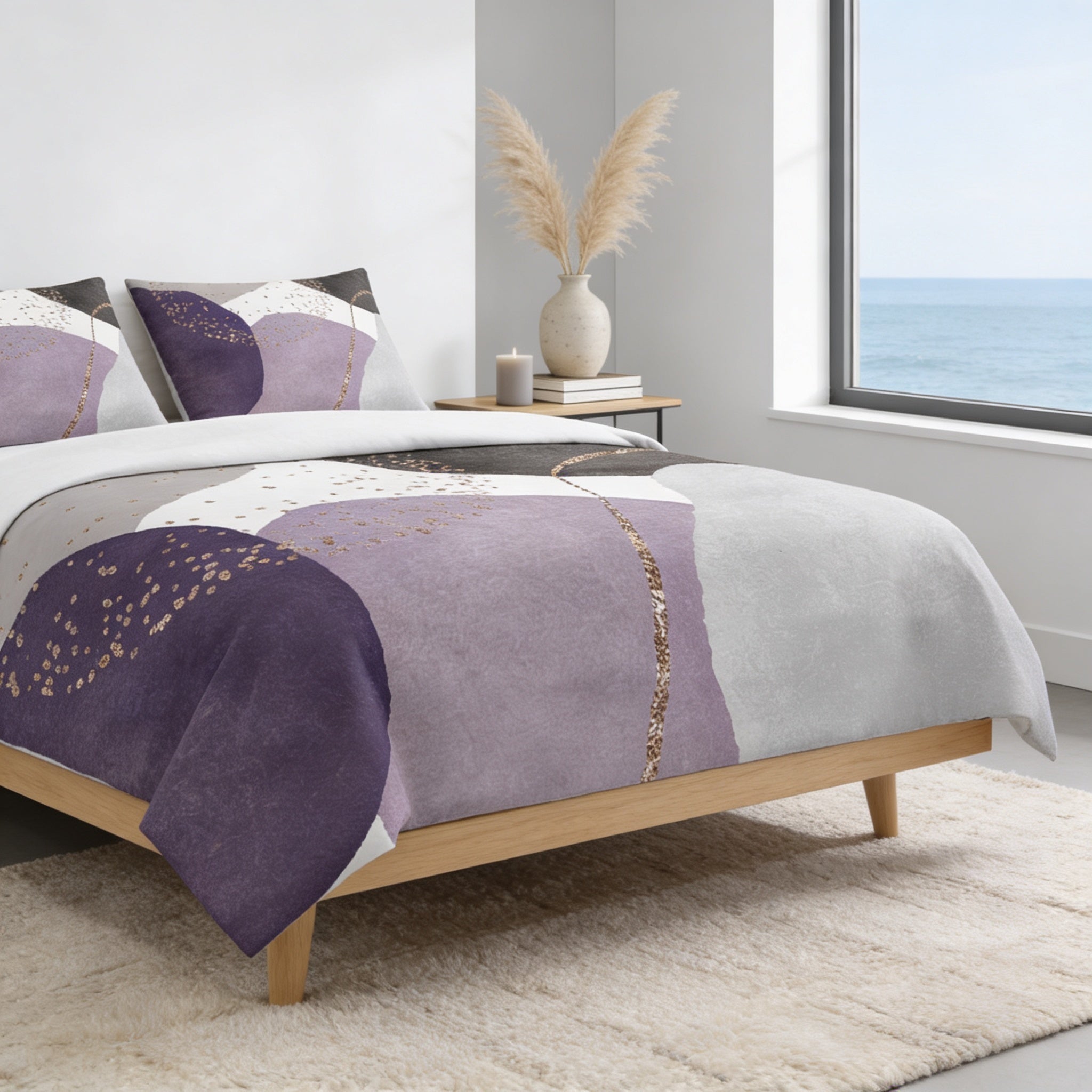 a modern bedroom with a large bed, a white wall, and a window overlooking the ocean. The bed is covered in a purple and white patterned comforter, and there are two pillows on the bed. A vase with potted plants is placed on a small table next to the bed, and a rug is laid out on the floor in front of the bed.