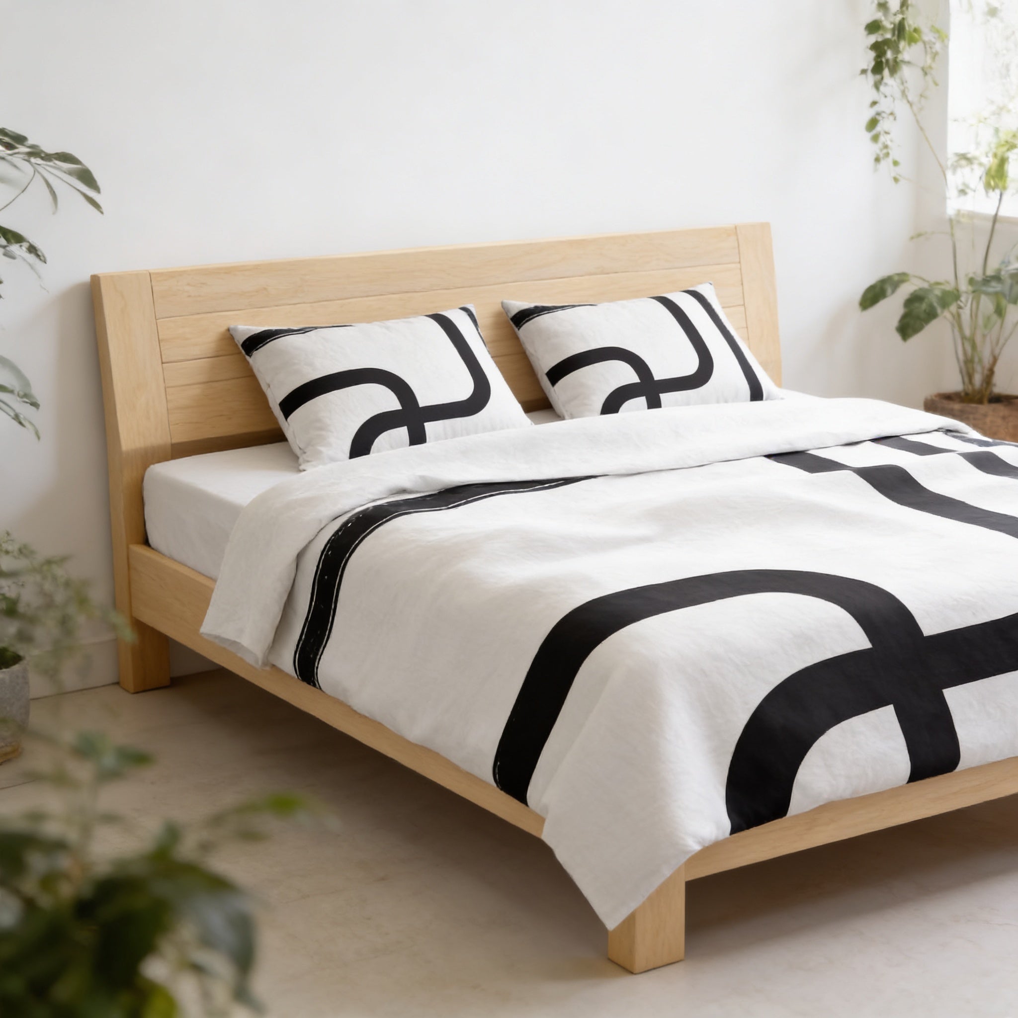 a modern bedroom with a wooden bed frame and a black and white patterned comforter. The bed is surrounded by potted plants, creating a cozy and natural atmosphere.